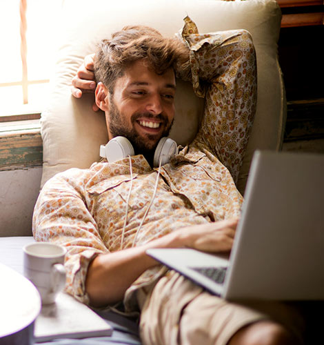 Man using laptop at home on couch.