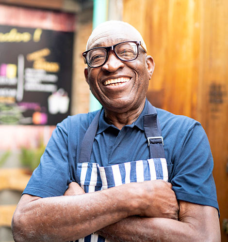 Man in apron in front of business.